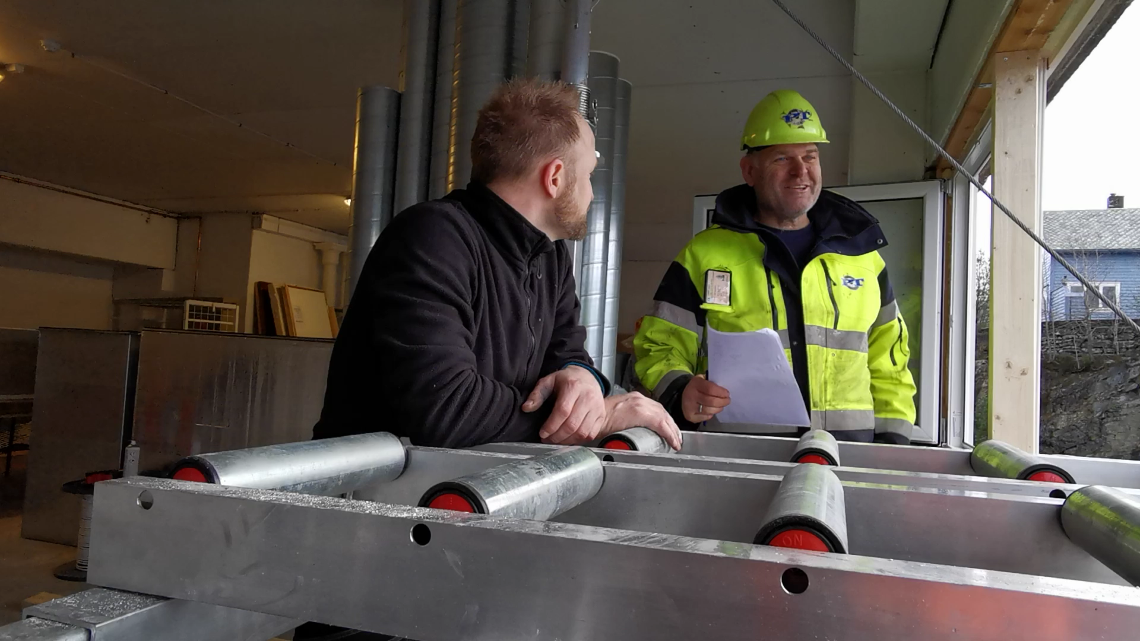 Gründer Ivar Ole Wik står ved rullene til Liftroller Wall, og snakker med kranfører fra Padøy Transport