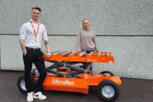 Joachim and Amalie standing in front of a grey wall, together with the Liftroller E Wagon