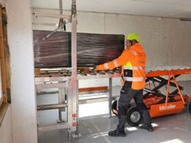 Inntransport på Packages of building materials are rolled onto the Liftroller system. A combination of the Landing ramp Liftroller Wall, the Material wagon Liftroller E Wagon and the plaster trestles Liftroller Trestle