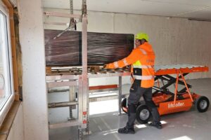 Packages of building materials are rolled onto the Liftroller system. A combination of the Landing ramp Liftroller Wall, the Material wagon Liftroller E Wagon and the plaster trestles Liftroller Trestle