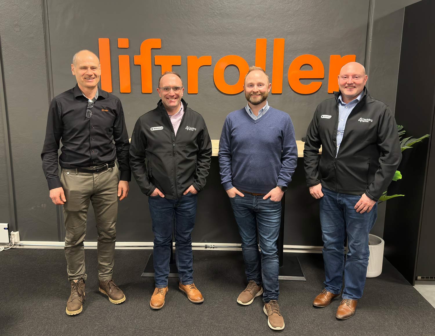 Helge Flesland_Tom Spence Ivar Ole Wik and Rob Barlow standing in front of a wall, smiling