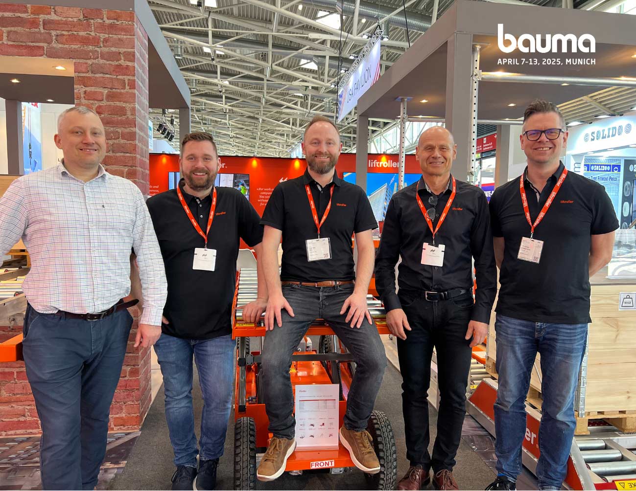 Team Liftroller standing in fron of the Liftroller stand at BAUMA 2025, in Munich